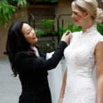Eine Designerin passt sorgfältig ein Hochzeitskleid an eine Braut in einem eleganten, begrünten Innenraum an.